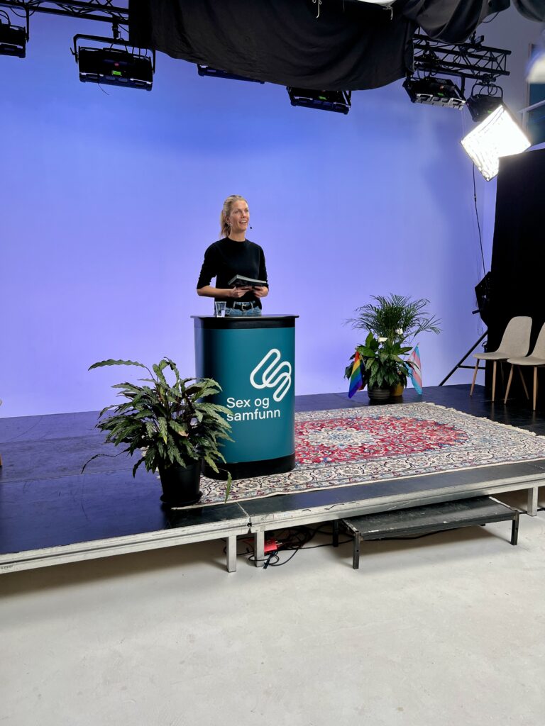 Fotografi av sykepleier Mari, som står på en scene og prater om vårt nye samtaletilbud under vår årlige konferanse HFU-dagene 2025